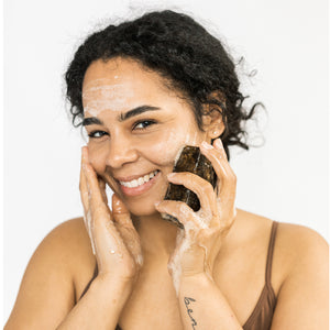 Model using the Scrub & Butter Black Soap Face + Body on her face.