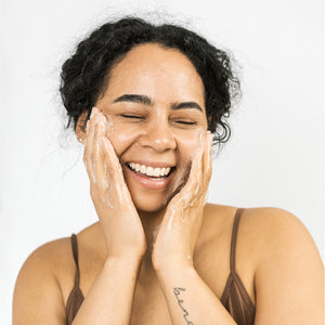 Model washing her face with Scrub & Butter Black Soap Face + Body.